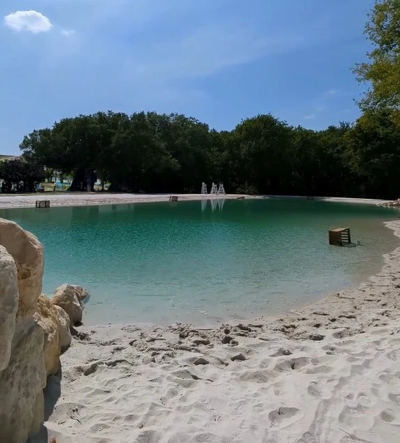 Vaste piscine lagon avec plage de sable et eau turquoise